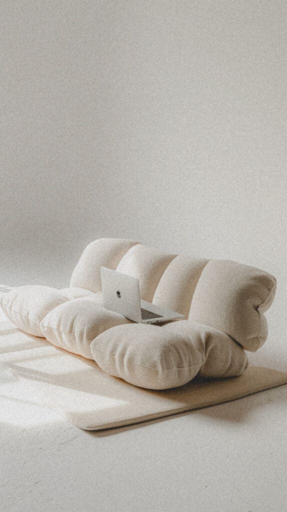 Laptop resting on a soft cream sofa in a bright, minimalist workspace.