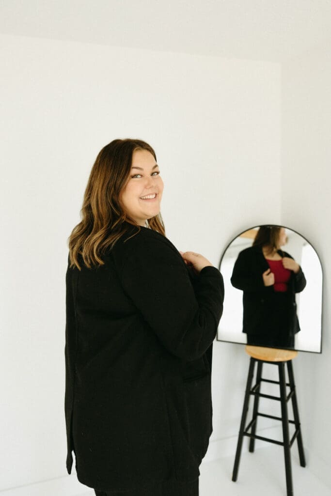 Creative business owner smiling beside a mirror, representing the confidence needed to build trust online.
