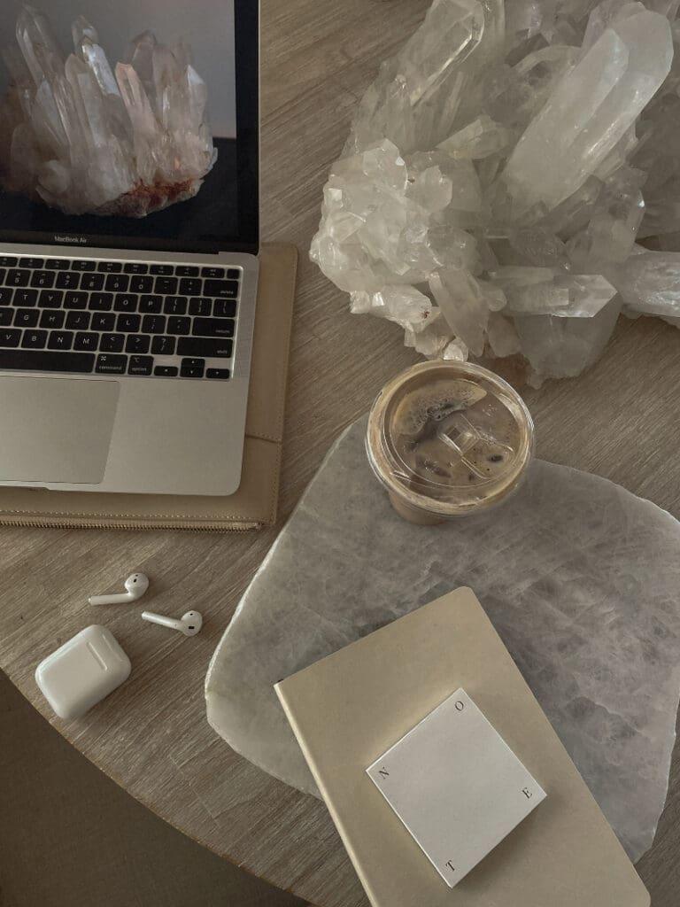 Laptop displaying crystal cluster beside large quartz formation, illustrating DIY website vs hiring a designer.