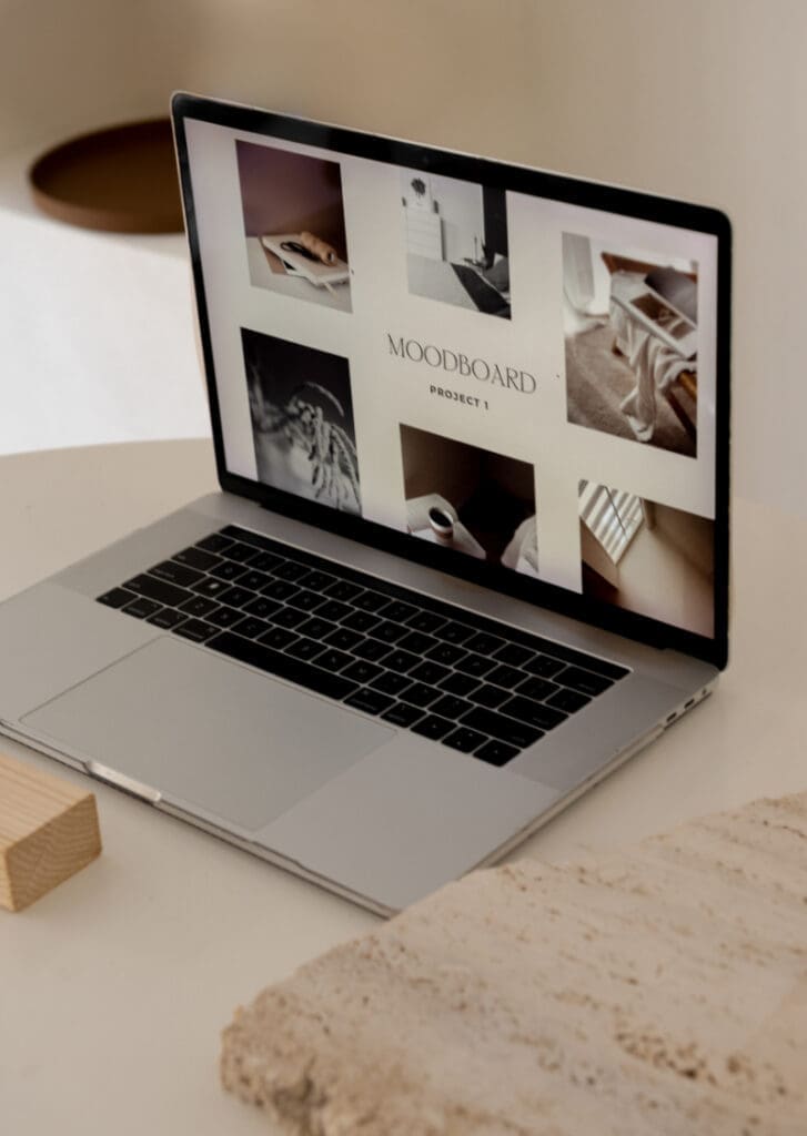 Laptop displaying a design mood board with neutral imagery and brand inspiration for a creative project