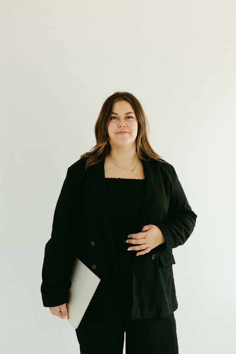 Business owner standing confidently in black attire, representing the rebrand strategy behind Haus of Mae.
