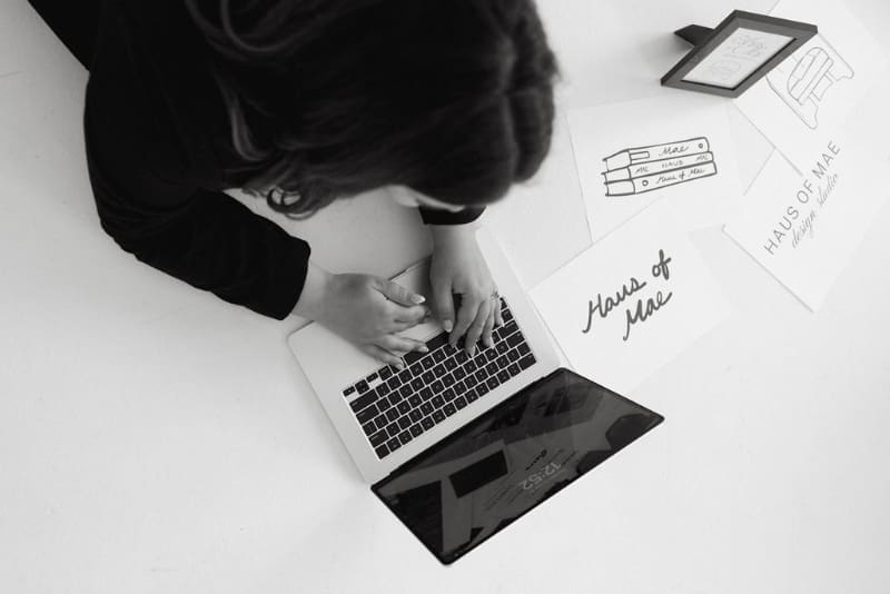 Overhead view of designer working on laptop with branding materials, clean workspace and intentional layout