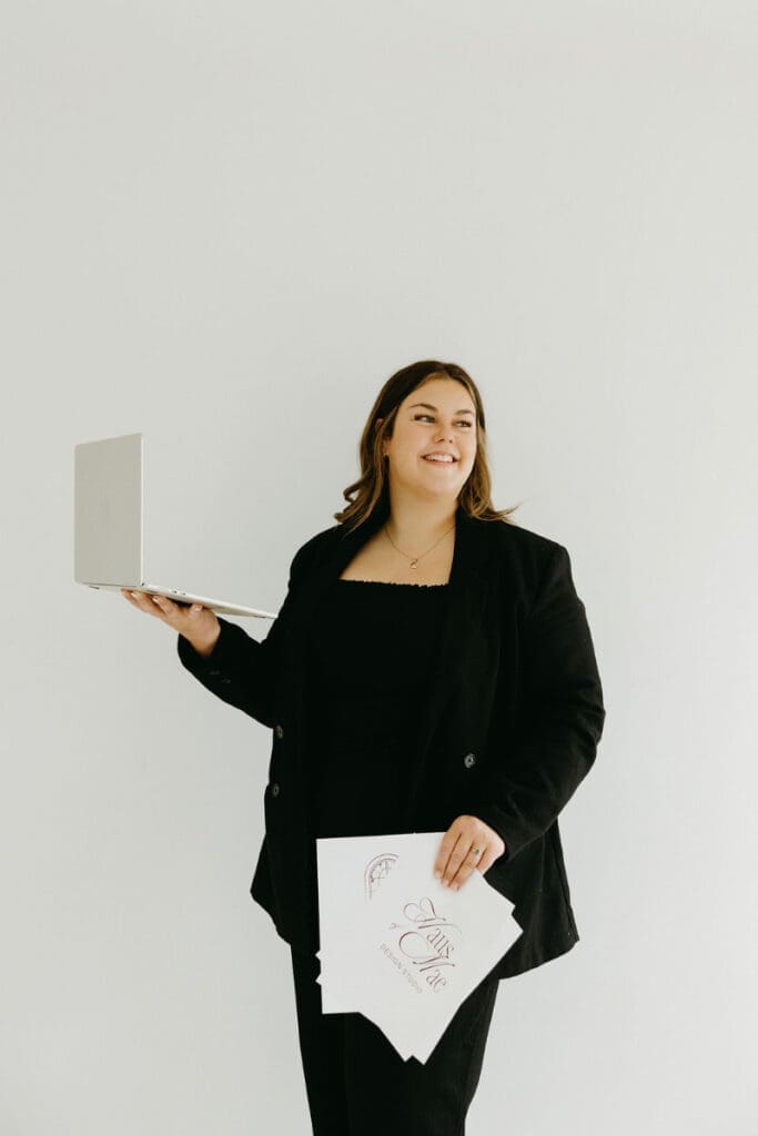 Creative business owner holding laptop, representing custom website vs template decision with clean, minimal aesthetic