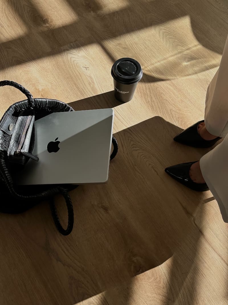 Website launch checklist workspace with laptop, coffee, and camera on wooden floor during setup