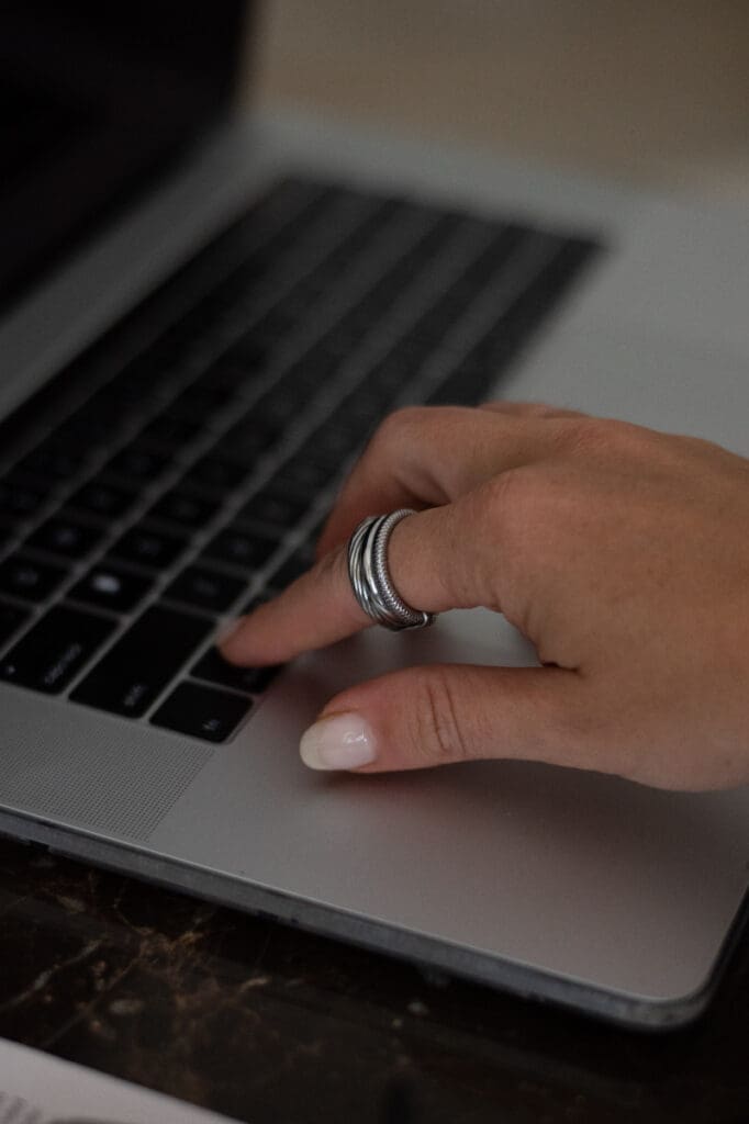 Hand typing on laptop keyboard while making website updates to improve content and user experience.